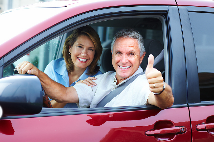 Satisfied couple driving recently delivered vehicle